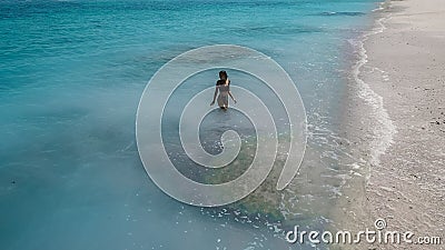 Young woman in a bikini at the white sand near the waves of blue sea. Bali, Indonesia. Aerial Shooting. Stunning tropical beach vi Stock Photo
