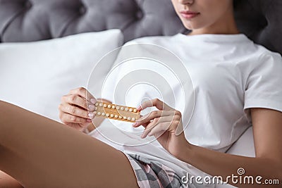 Young woman with birth control pills in bedroom Stock Photo