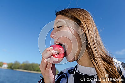 Young woman biting into a red apple with pleasure Stock Photo
