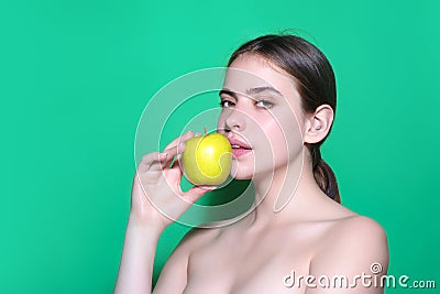 Young woman bitting apple, healthy lifestyle. Girls holds a fresh green apple studio portrait on green isolated Stock Photo