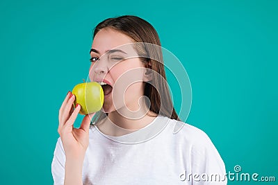 Young woman bitting apple, healthy lifestyle. Girls holds a fresh green apple studio portrait on green isolated Stock Photo