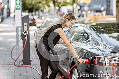 Woman charging electric car outdoors Stock Photo