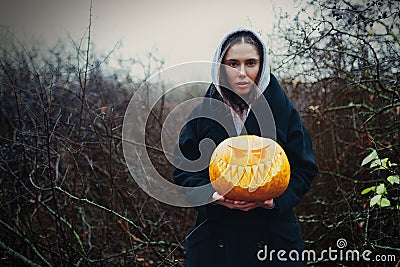 Young woman holding the halloween pumpkin in the autumn background Stock Photo