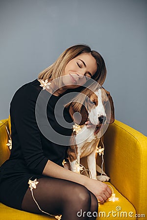 Woman hug puppy of beagle on yellow chair Stock Photo