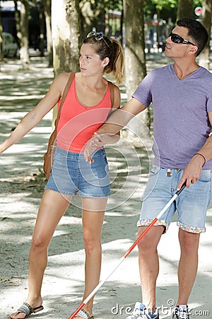 Young woman and blind man walking in park Stock Photo