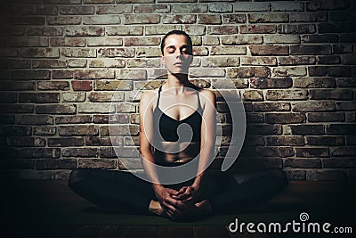 Young woman blond in black clothes practice yoga in dark studio Sport meditation Stock Photo