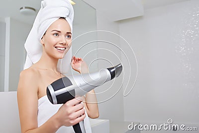 Young woman blow drying hair in bathroom Stock Photo