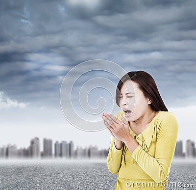 Young woman blowing to warm hands up with black clouds Stock Photo