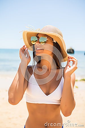 Young woman in blue bikini wearing white straw hat enjoying summer vacation at beach. Portrait of beautiful latin woman relaxing a Stock Photo