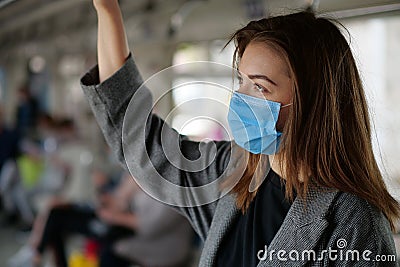 Young woman in medical protective mask rides in subway car Stock Photo