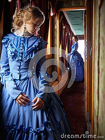 Young woman in blue vintage dress standing in corridor of retro Stock Photo