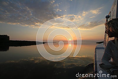 Young woman boating at sunset on the Danube Delta Stock Photo