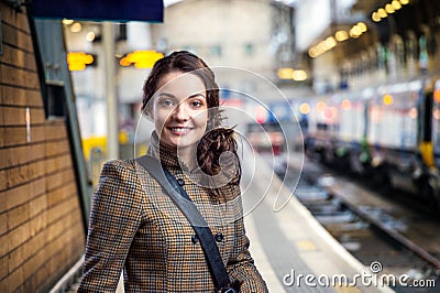 Young woman in brown winter coat waiting on train station Stock Photo