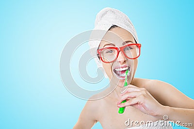 Young woman brushes teeth actively with toothbrush, opens mouth broadly, shows bare shoulders Stock Photo