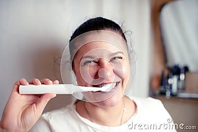 Young woman brushes teeth in bathroom an electric brush Stock Photo