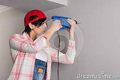 Young woman builder drill wall of old drill Stock Photo