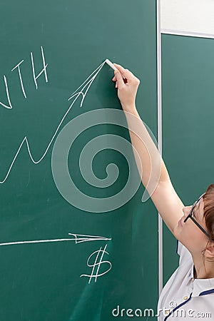 Young woman business coach in a white blouse and glasses at the chalkboard in the office draws a profit graph Stock Photo