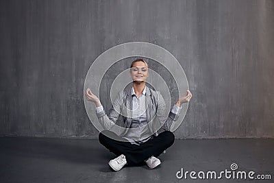 Young woman in business suit sitting in Lotus pose, restore energy, meditate. Health and work Stock Photo