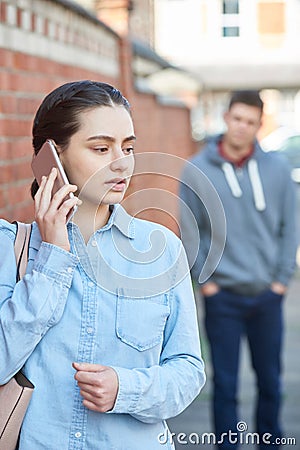 Young Woman Calling For Help On Mobile Phone Whilst Being Stalke Stock Photo