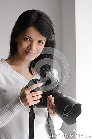 Young woman with camera. Portrait of beautiful young woman holding a camera and looking at you Stock Photo