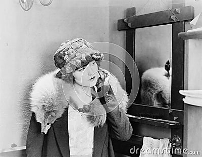 Young woman carrying a fox stole on her shoulders and adjusting her earring Stock Photo