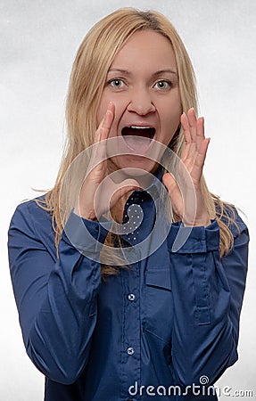 Young woman in casual blue shirt screaming and looking straight into camera Stock Photo