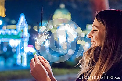Young woman celebrating an event the New Year is coming. She holding glittering sparkler on. Stock Photo