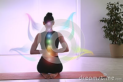 Young woman with chakra points practicing yoga in studio. Healing energy Stock Photo