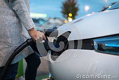 Young woman charging an electric vehicle Stock Photo