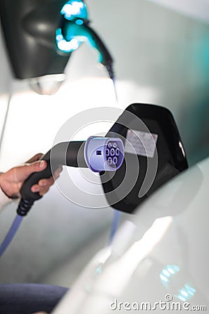 Young woman charging an electric vehicle Stock Photo