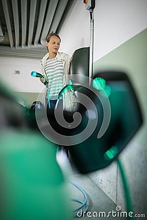 Young woman charging an electric vehicle Stock Photo