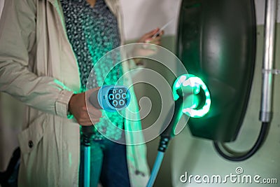 Young woman charging an electric vehicle in an underground garage Stock Photo