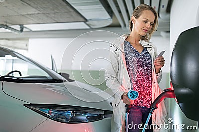 Young woman charging an electric vehicle Stock Photo