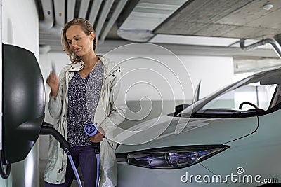 Young woman charging an electric vehicle Stock Photo