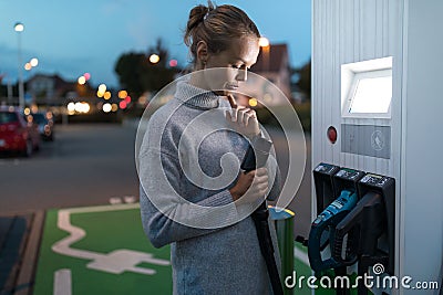 Young woman charging an electric vehicle Stock Photo