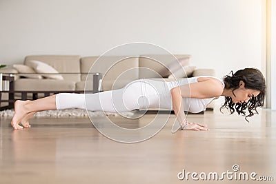 Young woman in chaturanga dandasana pose, hotel cozy living room Stock Photo