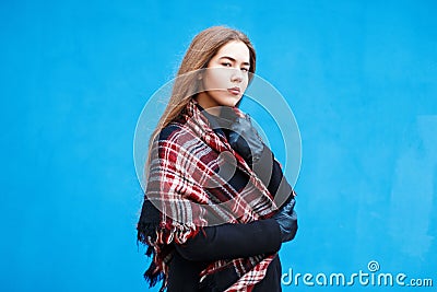 Young woman with a checkered red scarf near a blue wall Stock Photo