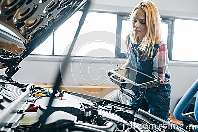 Young woman checking fuel economy, car timing, and performance characteristics. Stock Photo