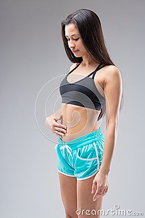 Young woman checks toned belly, defies societal pressures Stock Photo