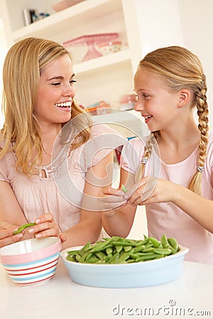 Young woman with child splitting pea in kitchen Stock Photo