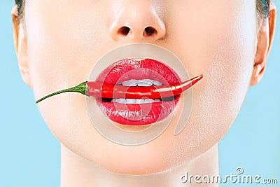 Young woman with chili red pepper isolated en blue background. Sexy female lips. Hot seductive girl Stock Photo