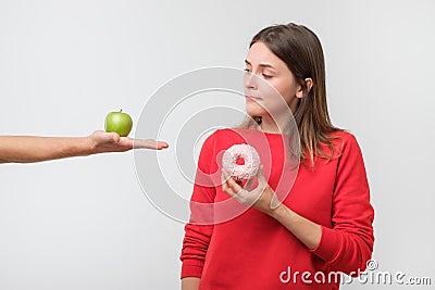 Young woman choosing between apple and donut Stock Photo