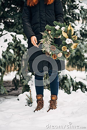 Young woman with Christmas wreath in winter snowy day. Copy space Christmas banner. Handmade eco decoration for winter Stock Photo