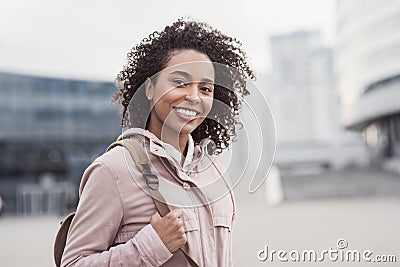 Young woman in a city looking at camera. African-american student girl portrait. Cute girl smiling. Stock Photo