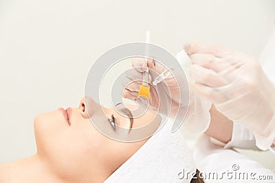 Young woman cleaning face skin in salon. Retinol peel with brush. Acid organic peeling Stock Photo