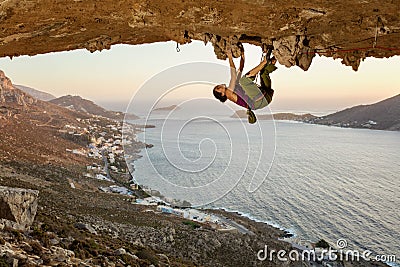 Young woman climbing in cave at sunset Stock Photo