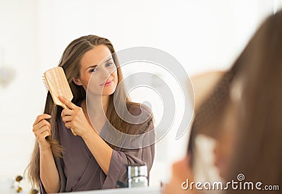 Young woman combing hair in bathroom Stock Photo