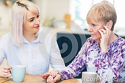 Young Woman Comforting Unhappy Senior Woman Suffering From Loneliness And Depression Stock Photo