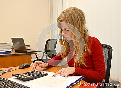 The young woman conducts calculation on the calculator at office Stock Photo