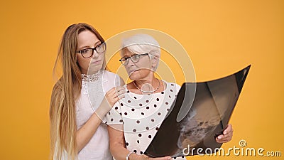 Young woman confronting worried senior lady holding a x-ray o MRI head scan Stock Photo